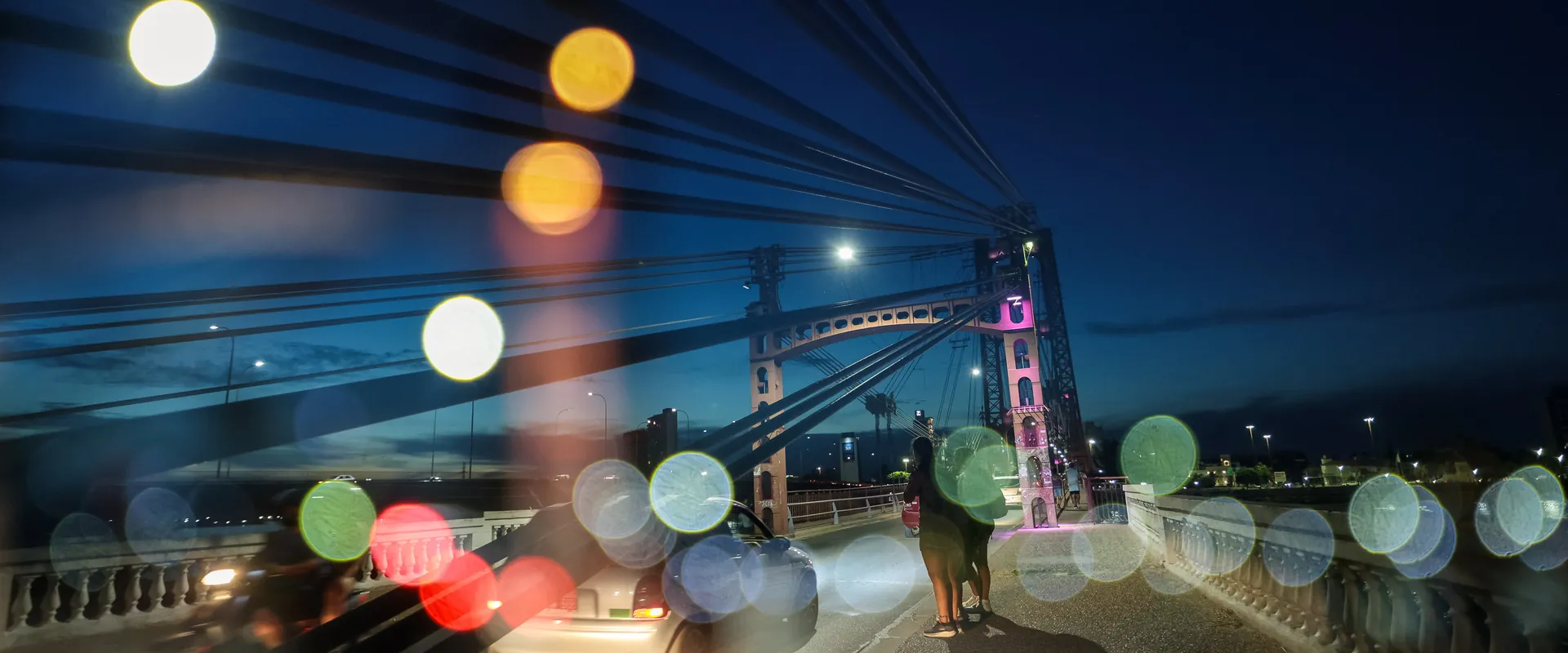 Fotografía nocturna del Puente Colgante de Santa Fe con efecto bokeh