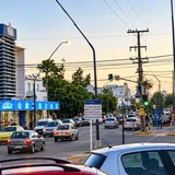 Vista urbana de la avenida General Paz en Santa Fe durante el atardecer, con tránsito vehicular regular y locales comerciales a ambos lados de la calle.